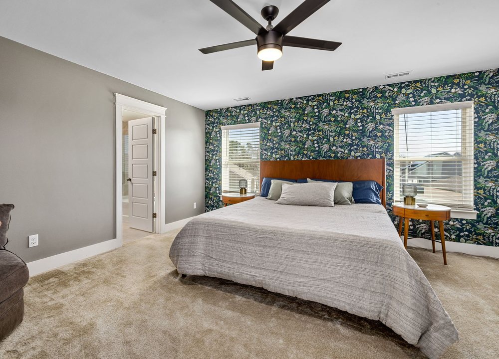 Bedroom with a deep-green botanical wallpaper feature wall behind the bed